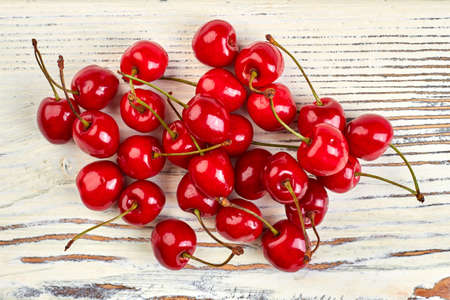 Heap of red cherries on wooden background. Fresh delicious berries on white wooden boards. Healthy...