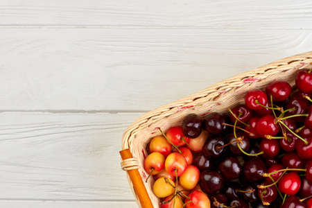 Fresh ripe cherries in basket and copy space. Sweet ripe cherries in basket on white wooden surface.の写真素材