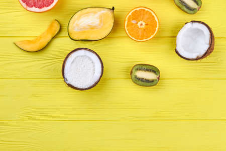 Flat lay colorful tropical fruits. Assortment of organic fruits cut in halves. Coconut with coconut flakes. Healthy nutritious fruits.の写真素材