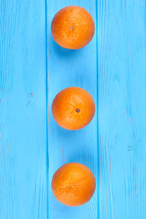 Row of ripe oranges, top view. Healthy orange fruits on blue wooden background with copy space.の写真素材