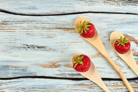 Wooden spoons with ripe strawberries. Red ripe strawberries placed on wooden spoons, copy space. Food and nature.の写真素材