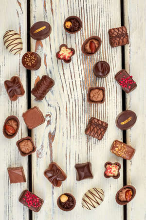 Frame from chocolates, top view. Assorted chocolate candies arranged in frame on old wooden...