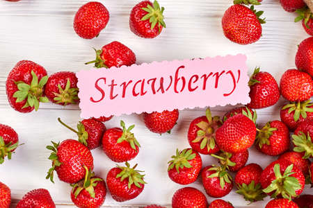 Fresh ripe strawberries background. Close up strawberries and pink paper message on white background. Healthy fruity background.の写真素材
