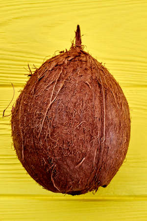 Whole tropical coconut fruit. Fresh organic coconut on yellow wooden background. Delicious exotic...
