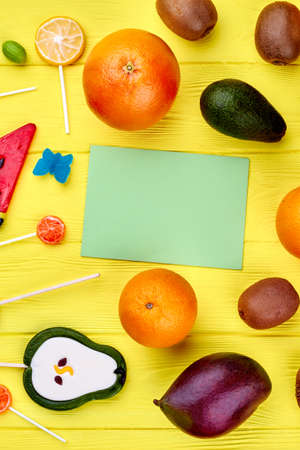 Mix of of organic fruits and candies. Fruits, candies and paper card. Healthy and unhealthy food concept.の写真素材