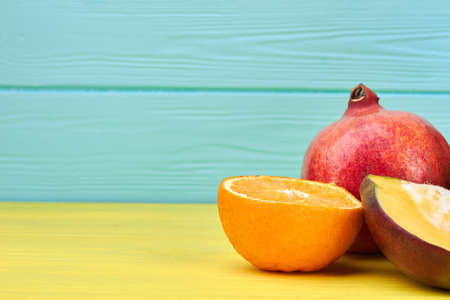 Ripe orange, pomegranate and grapefruit on color background. Side border with copy space from fresh tropical fruits. Healthy eating concept.の写真素材