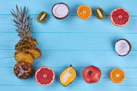Frame from exotic fruits on color background. Assortment of fresh sliced tropical fruits and copy...