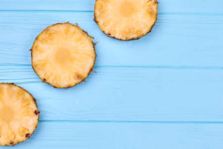 Border from pineapple slices and copy space. Three round circles of ananas on blue wooden surface with text space.の写真素材