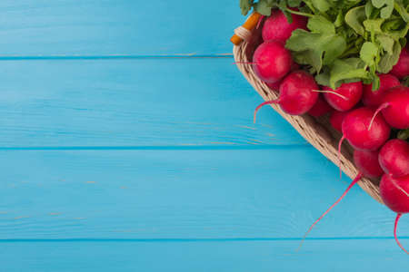 Wicked basket with reddish and blue wooden background. Close up. Vegetables and copyspace.