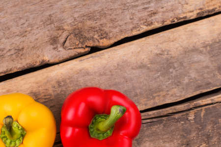 Two bell peppers on wood and copyspace. Yellow and red peppers, top view. Space for your text.の写真素材