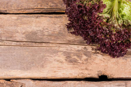 Leafy purple lettuce and copyspace. Top view. Old rustic wooden table background.