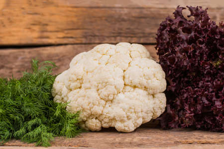 Raw vegetables for cook salad. Dill, white cauliflower and purple lettuce, close up. Old rustic...