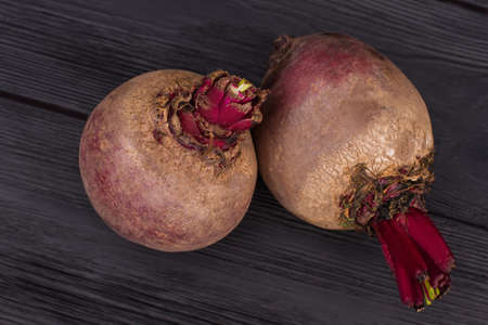 Purple raw organic beetroots. Close up, top view. Black wooden surface.