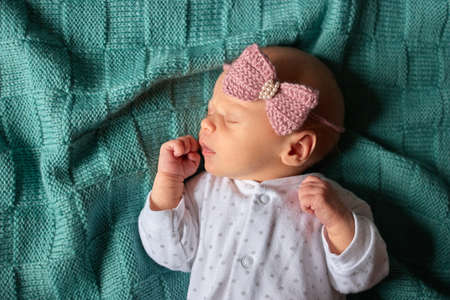 Sleeping newborn baby girl. Top view. Child on green wool clothes.