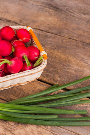 Cooking salad, fresh raw vegetables. Radishes and green onion. Wooden desk table background.の写真素材