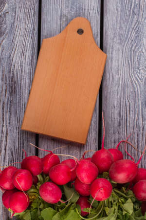 Cut board and radishes. Cooking preparing salad. Grey wood background.の写真素材