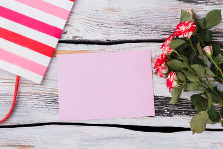 Blank purple paper and free space for text. Shopping bag, bunch of flowers. White wood background.の写真素材