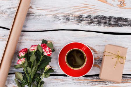 Morning coffee, flowers and gift. Top view, flat lay. White wood background.の写真素材