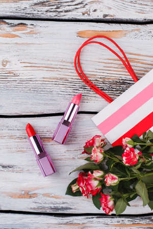 Female accessories, lipsticks and striped shopping bag. White wood background.の写真素材