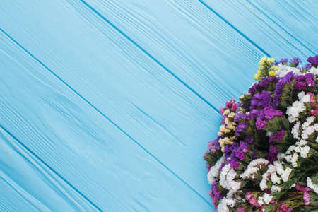 Multicolored limonium dry flowers on wood and copyspace. Free space for text. Blue wooden table...