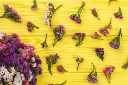 Sprinkled branches of limonium statice flowers on wood. Top view, flat lay. Yellow wooden background.の写真素材