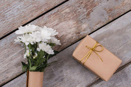 Bouquet of chamomile flowers and gift wrapped in paper. Vintage old wooden background.の写真素材
