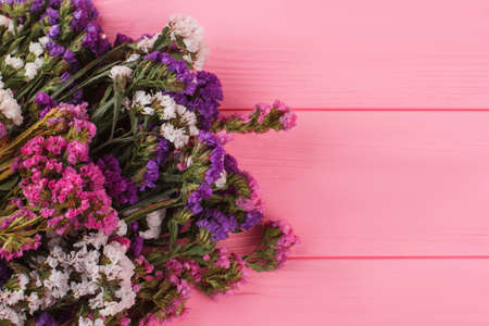 Colorful statice flowers on pink wooden background. Top view. Bouquet of flowers gift for girlfriend.の写真素材