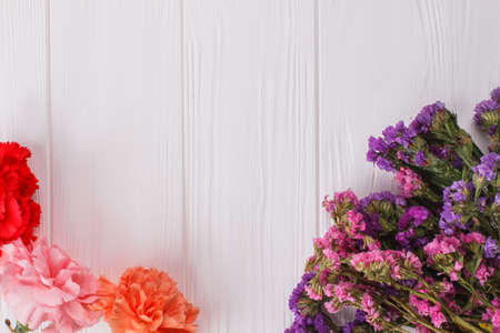 Carnation and statice limonium flowers on white wood. Top view. Close up.の写真素材