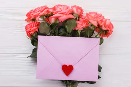 Romantic present for girlfriend or wife. Purple envelope with heart and rose flowers. White wooden...