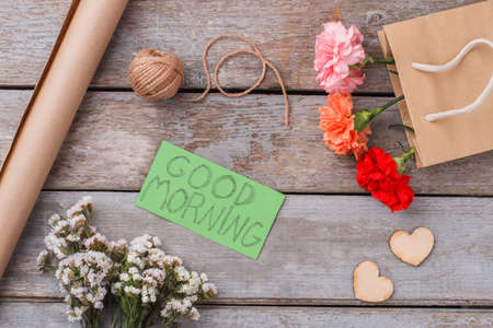 Flowers bouquets, handmade items and good morning wish note. Flat lay, top view. Old wooden table...