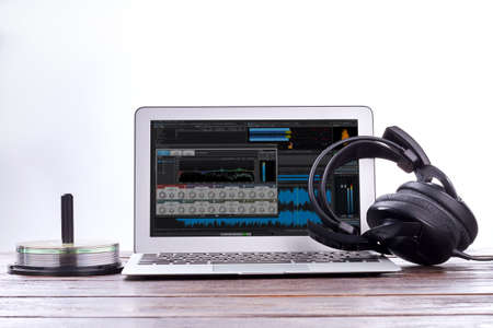 Laptop, headphones and disks. Earphones and pc notebook on wooden table. Modern technology concept.の写真素材