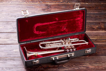 Golden trumpet in velvet case. Brassy trumpet in square box on wooden background. Classical music instrument.の写真素材
