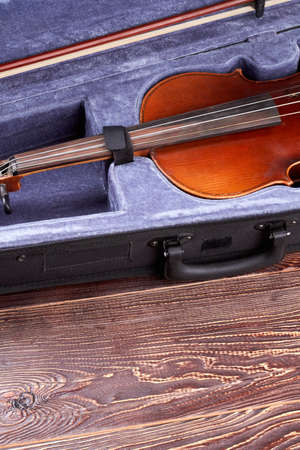 Retro violin in case and copy space. Musical instrument of orchestra on wooden background, vertical...
