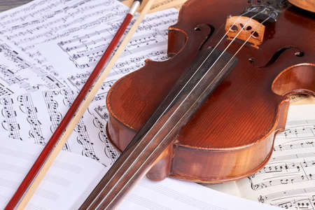 Vintage violin on musical notes. Old viola and musical notes sheets. Classical music background.の写真素材