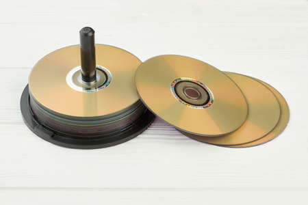 Stack of compact discs on white background. Group of blank disks on wooden surface. Digital storage of information.の写真素材