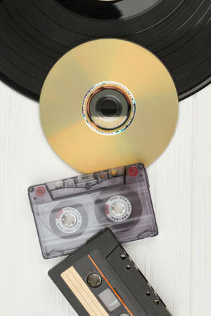 Vinyl record, audio tapes and compact disc. Top view on black vinyl plate, DVD disc, audio cassette...