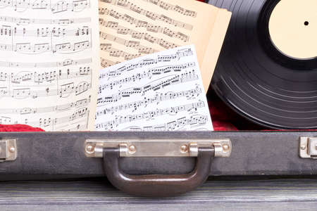 Close up musical notes and vinyl record. Case with musical notes sheets and plastic dics close up....