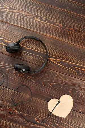 Headphones and plywood heart, top view. Headphones, wooden heart and copy space, vertical image. For...