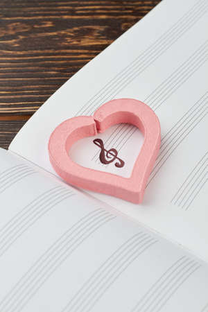 Pink heart on musical note book. Handwritten key and pink decorative heart on musical sheets. Music is love.の写真素材