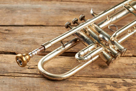 Old classical trumpet close up. Traditional wind instrument on old wooden floor.