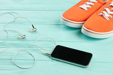 Female sport accessories on wooden background. Flat lay fitness items for women sport including sneakers, smartphone and earphones.の写真素材