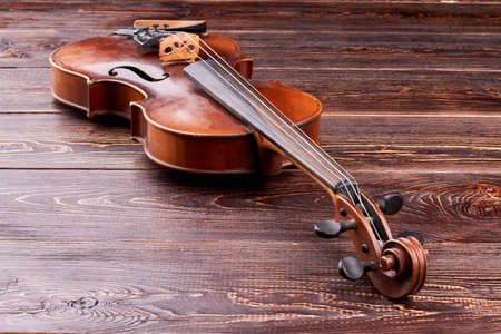 Violin on brown wooden background. Stringed musical instrument and copy space. Antique equipment of...