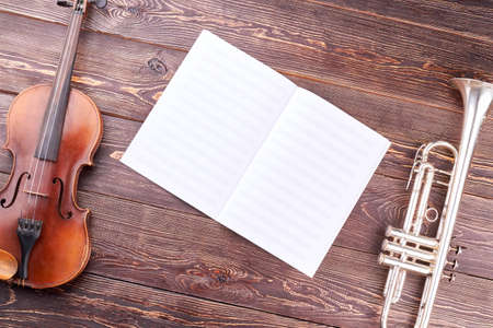 Old violin, trumpet and musical notes. Symphonic music instruments on wooden background. Orchestra...