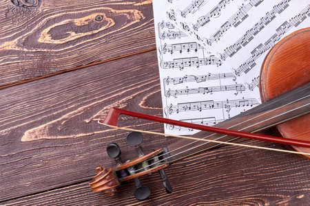 Violin, fiddle stick and musical notes. Old violin on textured wooden background, cropped image. Detail of violin.の写真素材