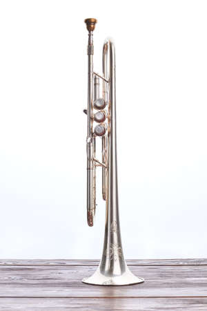 Trumpet instrument on wooden table. Silver trumpet over white background. Classical wind instrument.の写真素材