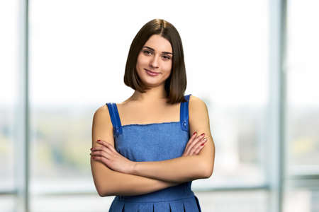 Pretty student with arms crossed. Cute cheerful girl standing with folded arms. Attractive smiling female.の写真素材