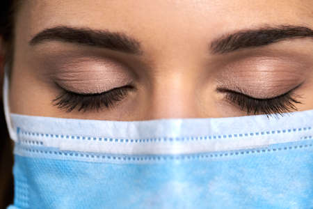 Female doctor in mask with closed eyes. Macro view female face in medical protective mask....