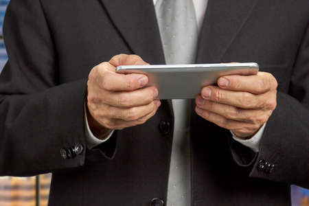 Close up mature businessman holding smartphone. Hands of middle-aged man in business suit holding smartphone close up. People, business, technology.の写真素材