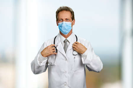 Male doctor with mask and stethoscope. Portrait of doctor man with face mask and stethoscope round neck.の写真素材