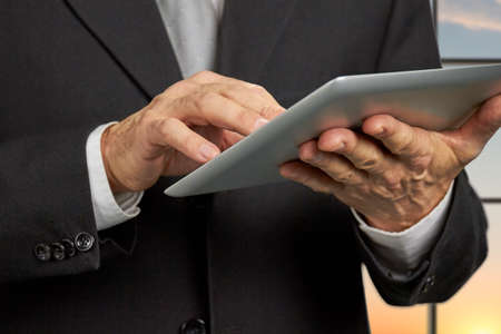 Close up businessman holding digital tablet. Mature man in business suit using computer tablet close up. People, business, technology.の写真素材